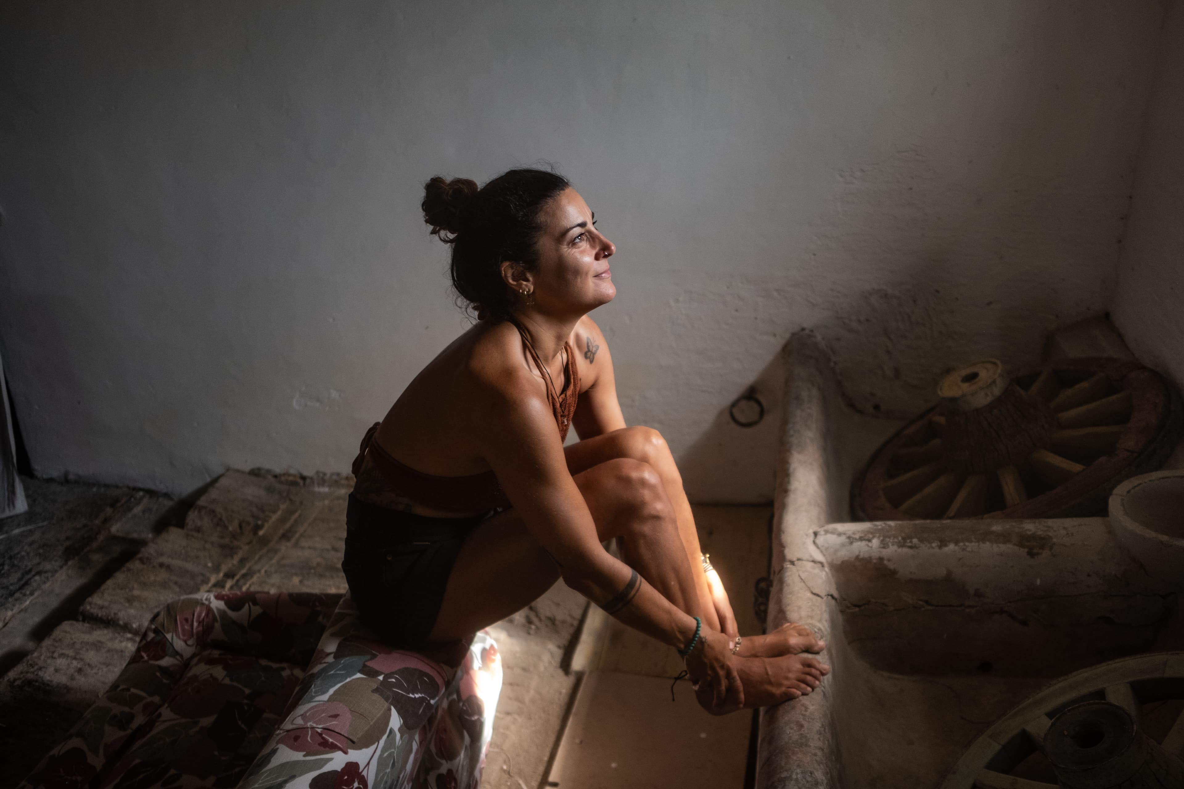 Woman seated in rustic environment looking upwards with serene expression